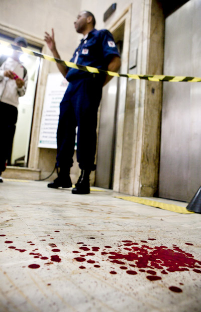 Seguranca ao lado de resquicios de sangue no interior do predio da Defensoria Publica do Estado de Sao Paulo, nesta quarta-feira, 25 de Abril de 2012. Um homem armado com uma faca e um martelo invadiu o predio no centro da cidade e, segundo a Policia, feriu seis pessoas, entre elas dois segurancas. (Foto: Gabo Morales/Folhapress)