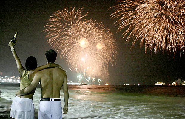 Casal observa queima de fogos durante Rveillon na praia de Copacabana, no Rio de Janeiro