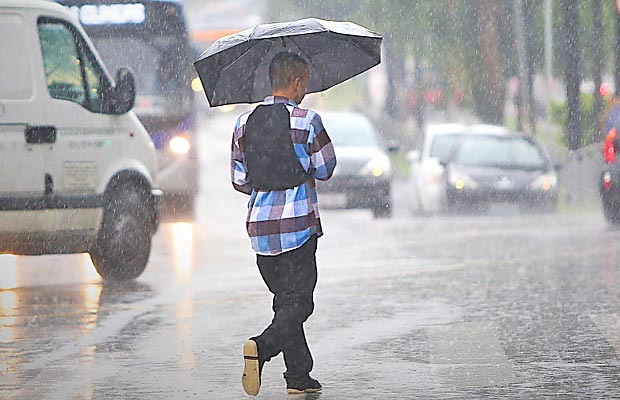 Jovem caminha sob a chuva na regio de Pinheiros (zona oeste); So Paulo tem o dia mais chuvoso do ano