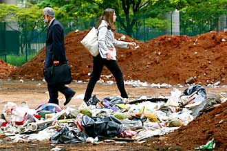 Pedestres caminham em meio ao lixo em praa