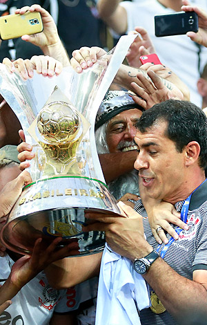Técnico do Corinthians, Fábio Carille recebe a taça do Brasileirão em meio à comemoração da torcida