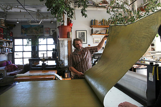Rob Swainston trabalha com impresso em corte de madeira em uma prensa gigante na cozinha de seu loft, em Nova York