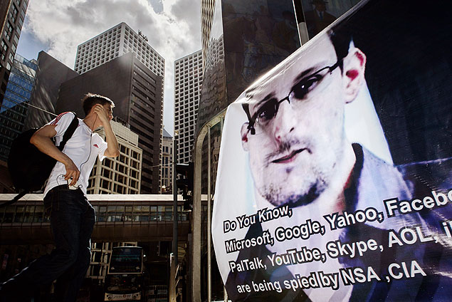 Homem olha para cartaz com foto de Edward Snowden