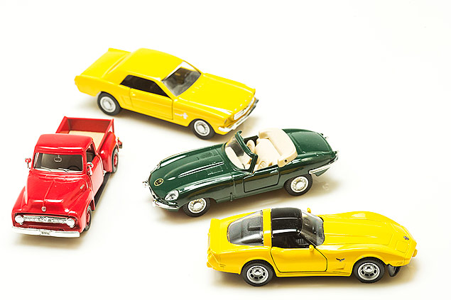 Ford Pick-Up 1953 (vermelho), Ford Mustang 1965, Jaguar E-Type Roadster 1961, Chevrolet Corvette 1982, em sentido horrio