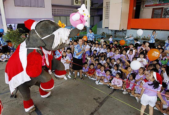 Elefante vestido de Papai Noel distribui presentes