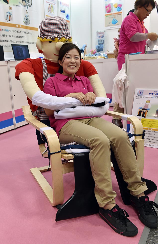 Funcionária da UniCare mostra "cadeira do abraço" na Feira Internacional de Reabilitação e Assistência no Lar de Tóquio