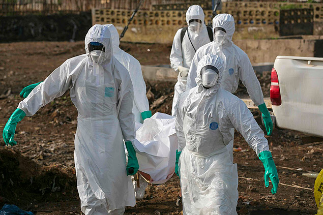 Homens com uniforme especial carregam corpo de pessoa infectada com ebola, em Serra Leoa