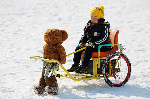 Urso de pelúcia robô conduz garotinho em minicharrete no parque Taoranting, em Pequim