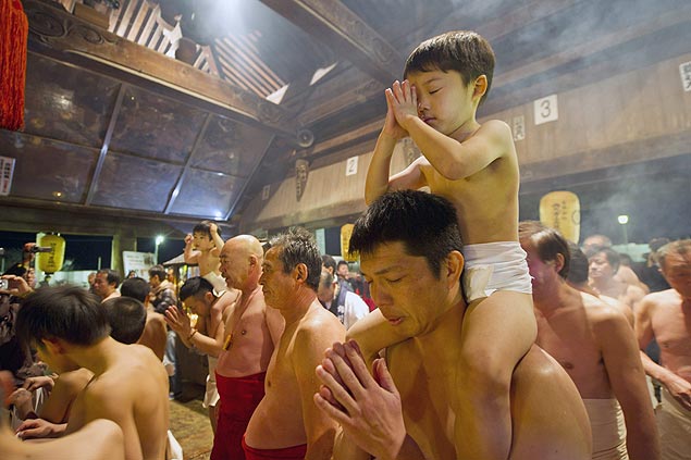 Pai e filho japoneses rezam em temperatura congelante dentro do Templo de Saidaiji em Okayama