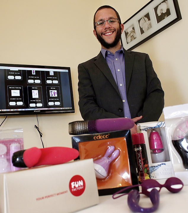Natan Alexander posa em seu escritório com os produtos que vende em seu site
