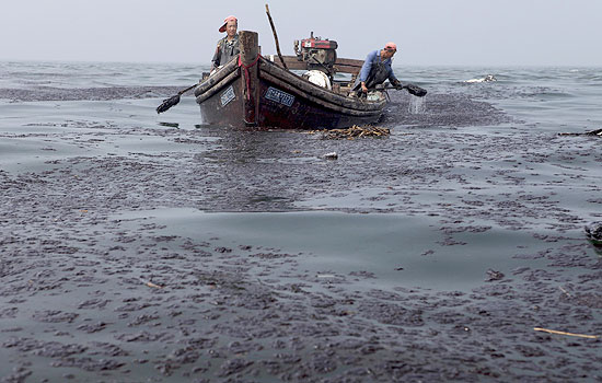 Pescadores limpam leo da regio de vazamento em Dalian; China anuncia controle do vazamento de petrleo