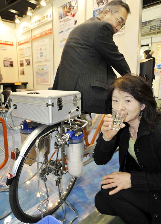 Expositora de feira de tecnologia sustentável, no Japão, mostra bicicleta que produz água filtrada