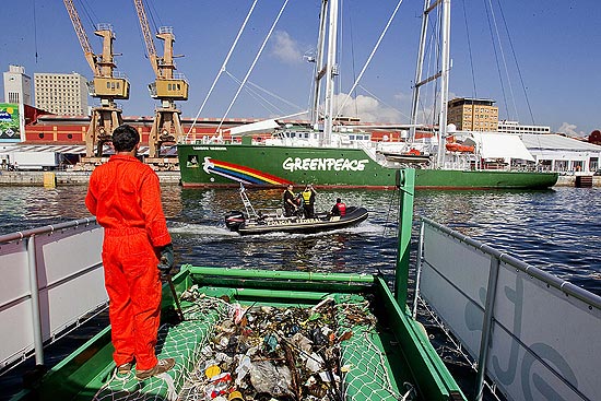 Funcionrio de empresa de coleta contratada recolhe lixo flutuante no mar; ao ser feita durante a Rio+20