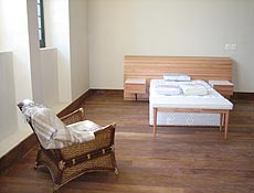 Quarto, de 50 metros quadrados tem uma cama, armrio, mesa para reunio e poltrona