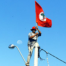 Membro do MST põe bandeira em frente à fazenda da Barra, em Ribeirão Preto, interior de SP