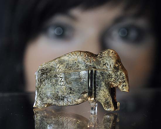 Funcionária do Museu de Neandertal, na Alemanha, exibe peça de marfim que reproduz um mamute