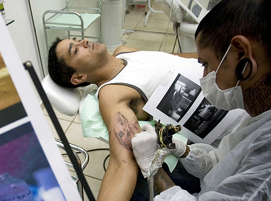 Homem durante sessão de tatuagem; processo ainda é demorado e pode levar meses até desenho ser concluído