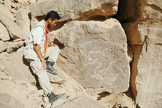 Membro da equipe de escavação ao lado das gravuras egípcias que foram encontradas em Qurta