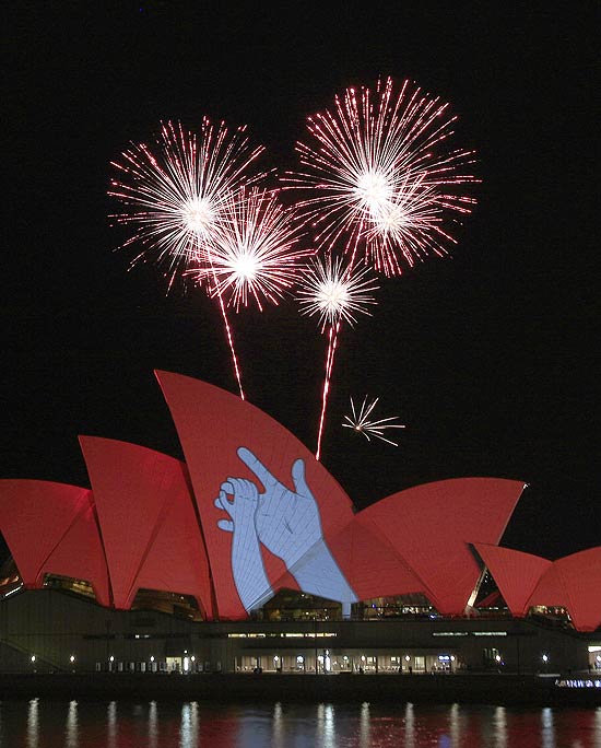 Fogos de artifício estouram atrás da Ópera de Sydney, pintada de vermelho para campanha contra a Aids