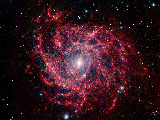 A galáxia IC 342 emite pouco brilho; a parte vermelha é a poeira estelar e a azul representa estrelas