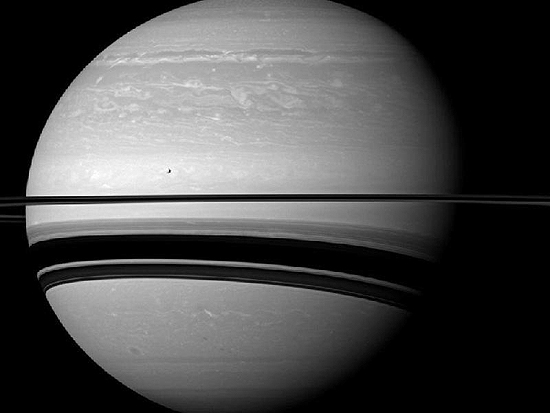 A lua Tétis aparece à esquerda da imagem, um pouco acima de um dos anéis de Saturno