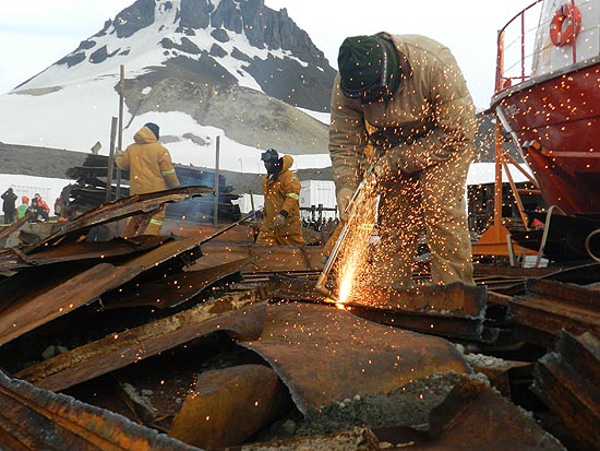 Operrio trabalha removendo os escombros da base antrtica, um ano aps o incndio que destruiu estao