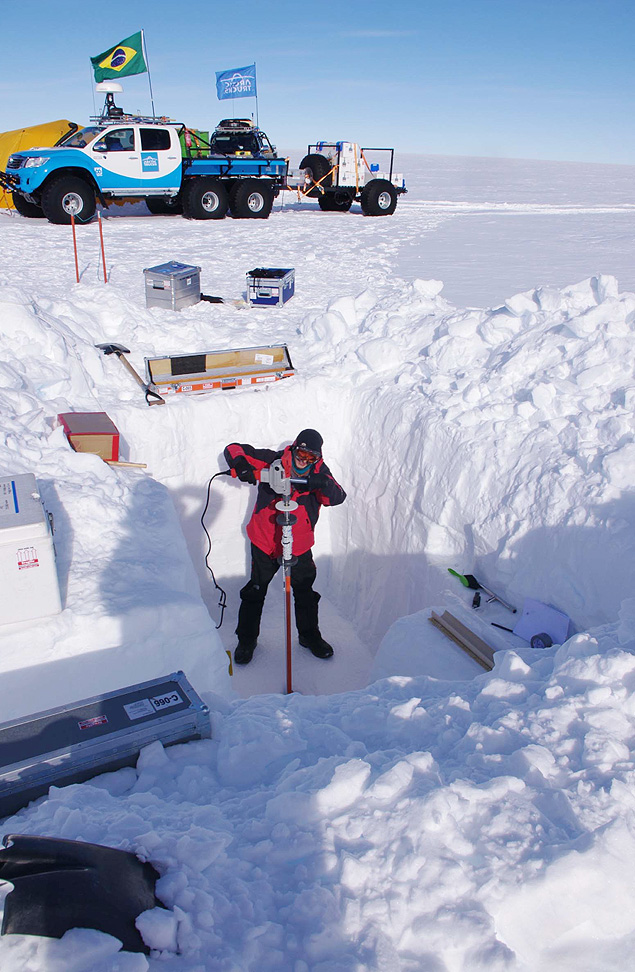 Pesquisador em trincheira, cavada na neve da Antrtida, coleta 'testemunho de gelo' do solo