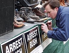 Americano prega cartaz com os dizeres "Prendam Bush" durante tarde de protestos contra o ex-presidente