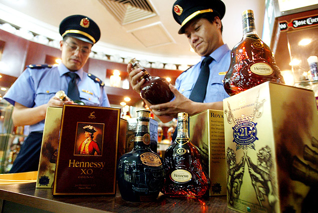 Policiais do escritrio de administrao de indstria e comrcio da China confiscam garrafas de conhaque francs falsificado em boate de Pequim
