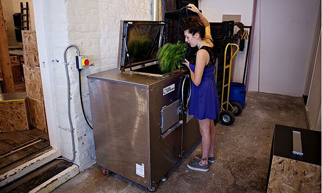 Funcionria despeja restos de alimentos na mquina de compostagem 