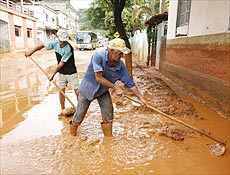 Homens limpam ruas em Mira aps rompimento de barragem de mineradora