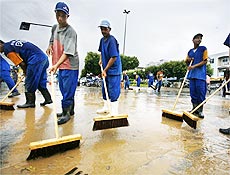Funcionrios da Prefeitura de Mira, em Minas Gerais, limpam lama aps inundao