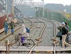 Moradores da região de Kobe atravessam ferrovia entortada por terremoto, em 1995