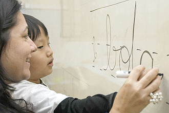 A profesora Silvana D'Ambrosio, do colégio Sion, na cidade de São Paulo, ajuda o aluno Mateus Yoona fazer letra cursiva