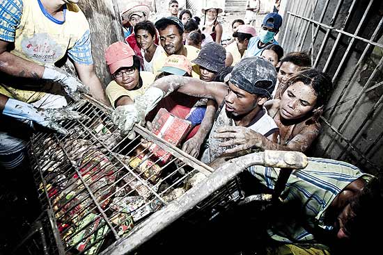 Pessoas recolhem restos de alimentos totalmente enlameados e estragados em supermercado em Palmares (PE)