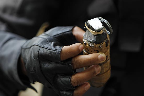 Policial mostra granada que foi encontrada em jardim de condomnio por onde os traficantes passaram