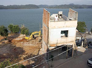Pedreiro Jesuino Ferreira observa máquina derrubar casas ao lado da sua, que também será derrubada, para obras em SP