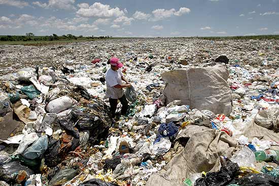 Catadora de lixo reciclável durante trabalho em lixão; um a cada quatro sacos de lixo vai para local impróprio