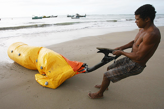 Pescador retira do mar destroos do helicptero que caiu prximo  praia de Itapororoca, em Carava (BA) ontem  noite