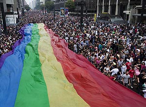 Multidão estende bandeira com referência aos gays e dança atrás do terceiro trio elétrico no desfile da avenida Paulista