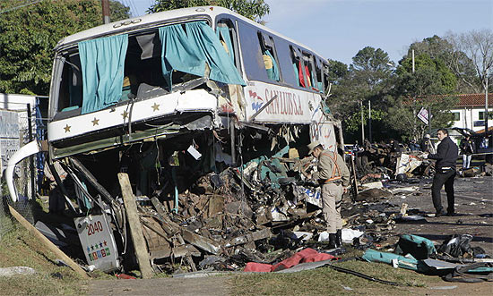 Policiais observam ônibus destruído após colisão com caminhão de de placa brasileira, no Paraguai