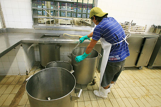 Aluno da UFSCar durante limpeza de panela na cozinha do restaurante, ocupado por alunos, em São Carlos