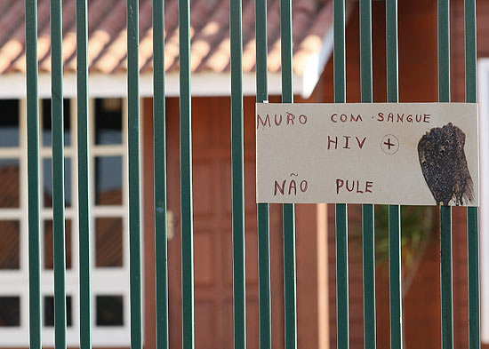 Cartaz com a informação "Muro com sangue HIV +, não pule" permanece na casa; seringas foram retiradas