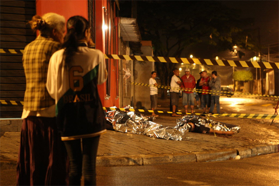 Pessoas observam corpos de vítimas de chacina em bar no Jardim Santa Maria, em Guarulhos