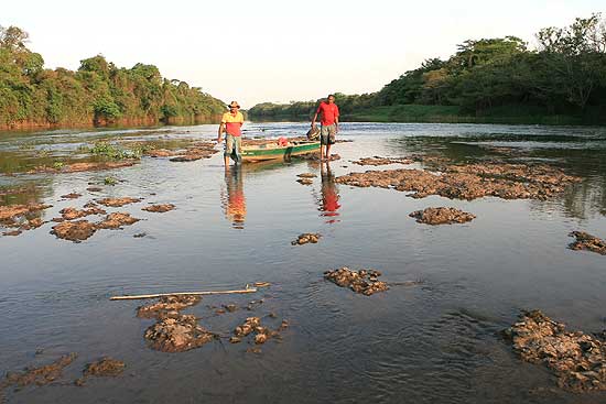 Pescadores caminham em trecho do leito do rio Pardo, onde rochas ficam aparentes pelo baixo nvel da gua
