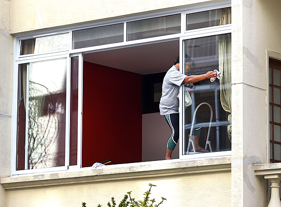 homem e mulher arrumando a casa, limpando o vidro da janela