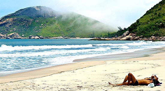 Banhistas aproveitamo sol e a areia branca na praia do Meio, na zona oeste do Rio