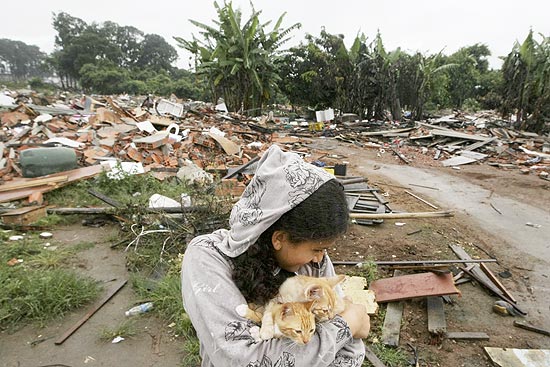 Menina com gatos no colo em meio aos escombros das casas demolidas no Pinheirinho