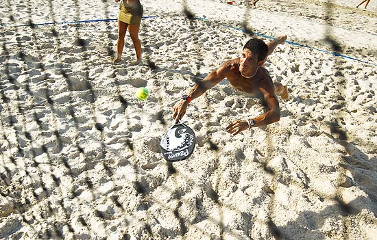 Homem prativa Beach Tenis na areia da praia de Copacabana, no Rio; esporte mistura frescobol, vlei e tnis
