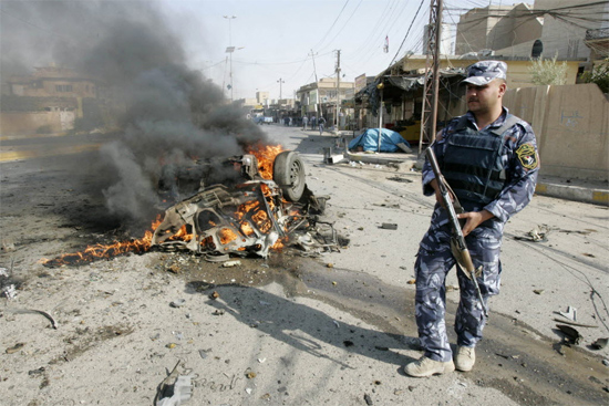 Policial observa carro em chamas em Kirkuk; série de atendados deixaram ao menos 50 mortos